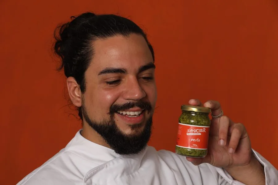 Mauricio Lacerda, chef e fundador da Saucier, sorrindo com um pote de pesto na mão