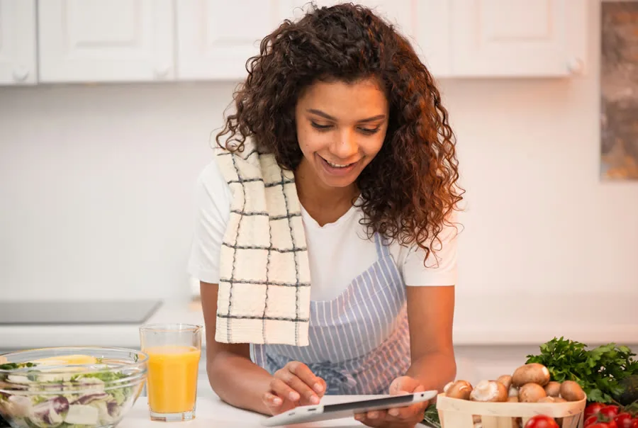 Mulher cozinhando enquanto consulta receita no tablet