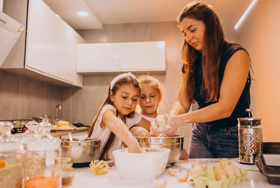 Mãe cozinhando com as filhas na cozinha